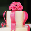Elegant two-tiered cake with pink ribbon and flower detailing